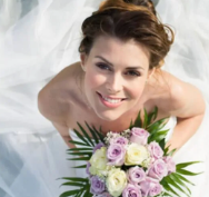 Glowing bride in her dress holding a flower bouquet on her wedding day